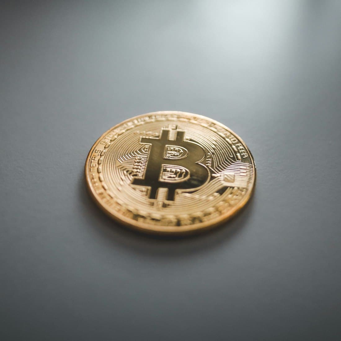 A gold Bitcoin coin resting on a dark surface